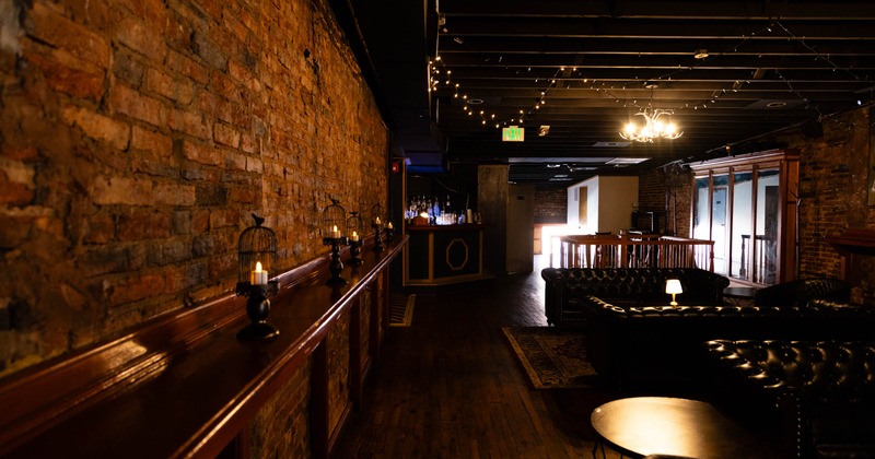 Wooden table along the brick wall, and black leather sofas