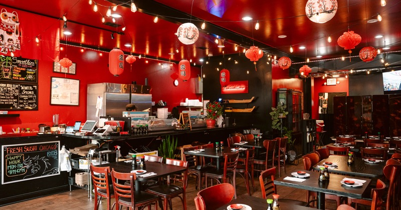 Interior view of a restaurant with red walls, wooden tables set for diners, decorative lanterns