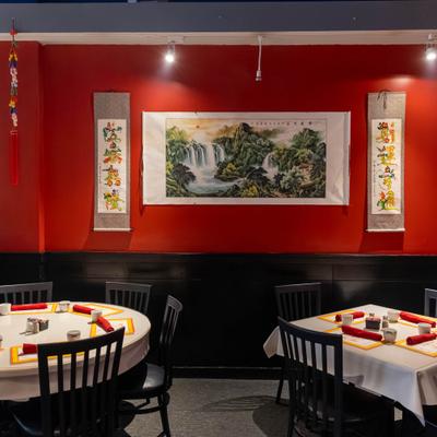 Red wall with landscape painting above dining tables.