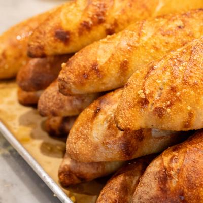 Stacked golden-brown baguettes on a tray.