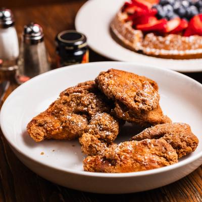 Plate of fried chicken, alongside a waffle topped with berries.