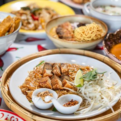 A Thai food spread featuring Pad Thai with crispy pork and condiments.