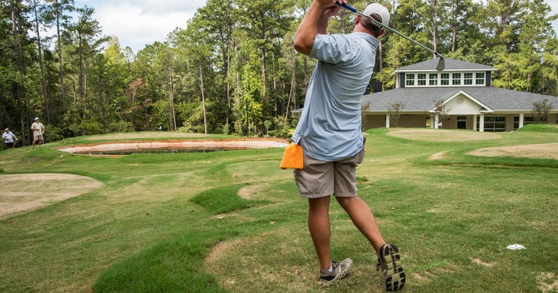 A golf swings a golf club, back view