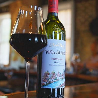 A glass of red wine next to a bottle.