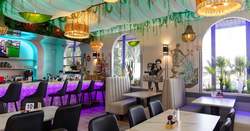 Interior, colorful decor, a bar counter with purple lighting, and an artistic mural on the wall