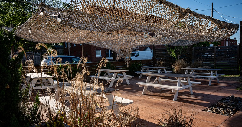 Outdoor seating area, wooden tables with benches and sun shades