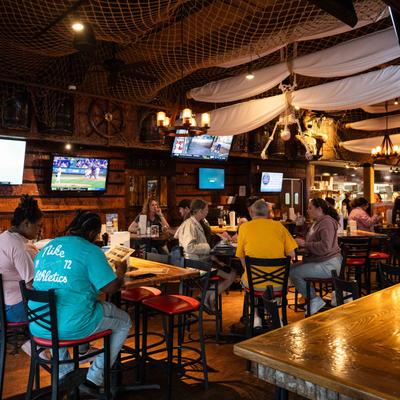 Rustic bar with patrons seated at tables.