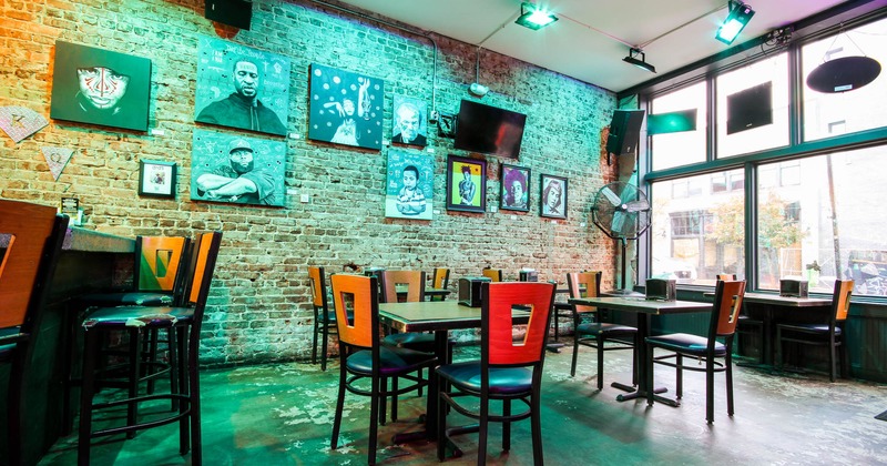 Interior, tables and seats near the bar, brick wall decorated with painting artwork