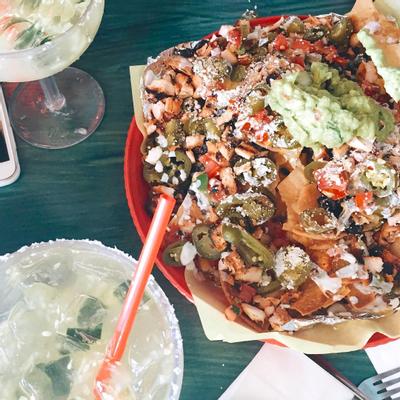 A glass of cocktail and nachos served, top view