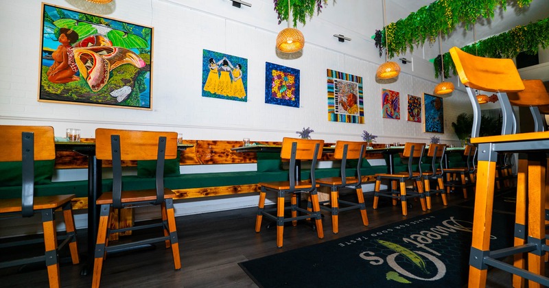 Interior, dining area, wooden banquette bench with tables and chairs, paintings on the wall