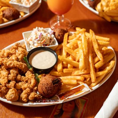 Southern fried shrimp served alongside fries, coleslaw, hushpuppies, and creamy sauce.