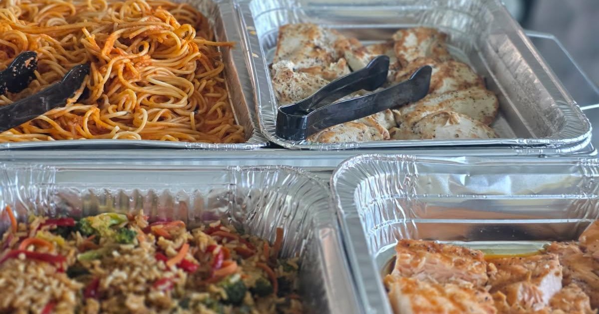Catering set up with a variety of dishes including fried rice, salmon, chicken, pork dumplings, pasta