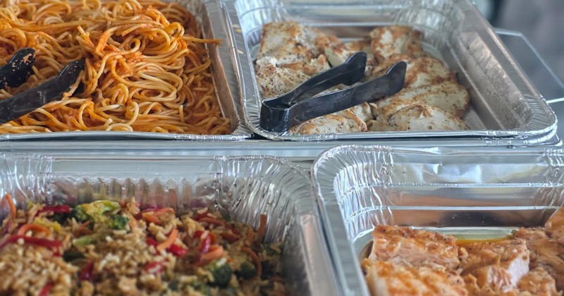 Catering set up with a variety of dishes including fried rice, salmon, chicken, pork dumplings, pasta