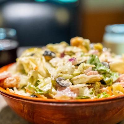 Creamy mixed salad with lettuce, olives, onions, tomatoes, and croutons.