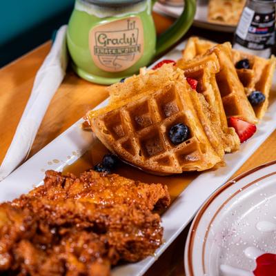 Waffles topped with berries and maple syrup, served with fried chicken.