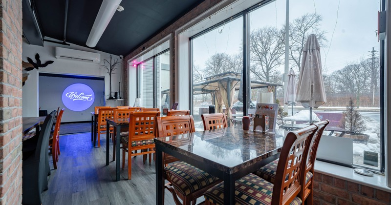 Restaurant interior with wooden tables and chairs, large windows