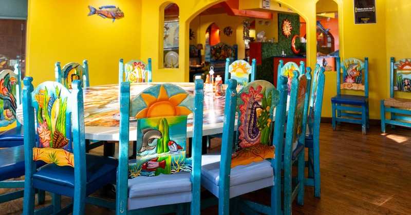 Interior of a colorful restaurant with marine-themed chairs and yellow walls