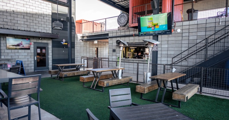 Covered patio, conjoined tables and benches, TV above