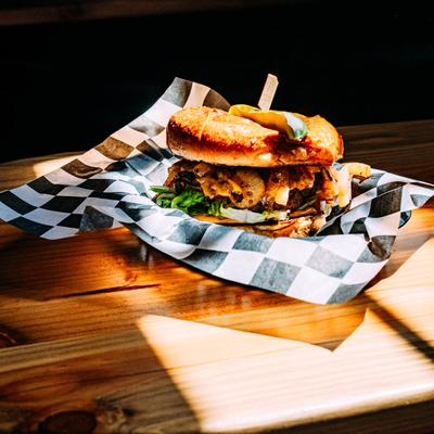 Bacon and mushroom cheeseburger served on checkered paper.