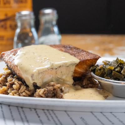 Grilled fish with creamy sauce served with greens and rice.