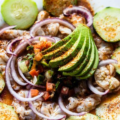 Aguachile with sliced avocado, red onion, cucumber, and pico de gallo.