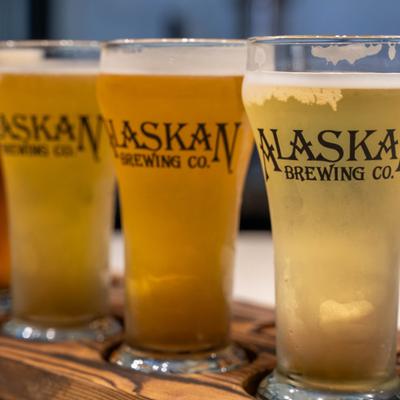 Beer flight featuring four branded tasting glasses served on a wooden tray.