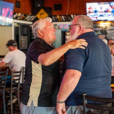 Two individuals interacting indoors in a bar setting.