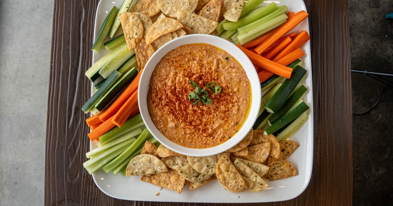 A platter with hummus, crackers and veggies