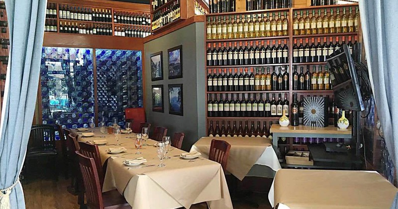 Interior, dining table in the corner of the room with wine shelves