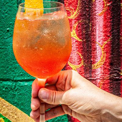 Closeup of a hand holding a glass with orange cocktail