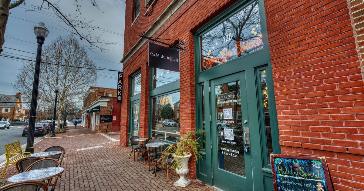 Brick wall exterior with entrance, signes and outdoor seating with small tables and chairs