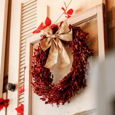 Decorative wreath with red leaves and gold ribbon hanging on the door.