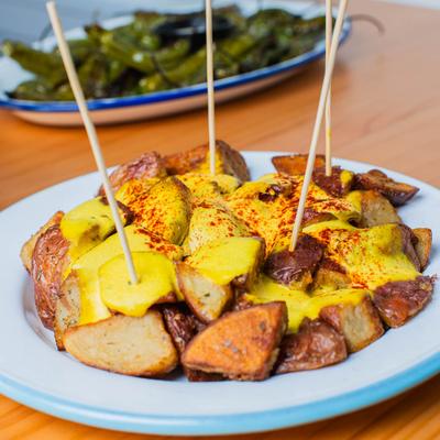 Papas bravas topped with yellow sauce.