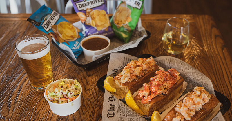 Three sandwiches, glass of beer, dip, salad and snacks on the side