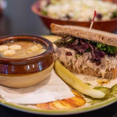 A bowl of soup with crackers and a turkey sandwich on whole-grain bread with lettuce.