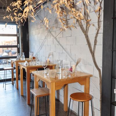 Interior with wooden tables and chairs, large windows and decorative plant