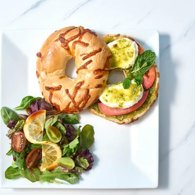 Bagel sandwich with basil pesto, mozzarella, and tomato.