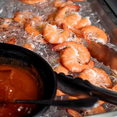 Chilled shrimp on ice served alongside a bowl of savory cocktail sauce.