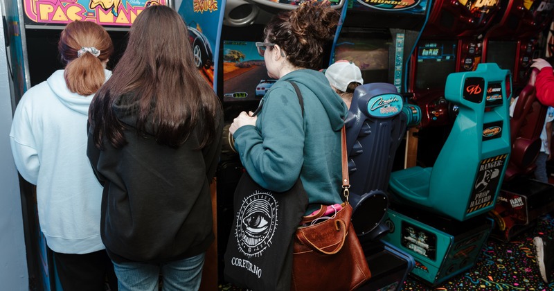 Two people standing in front of two vintage video game machines