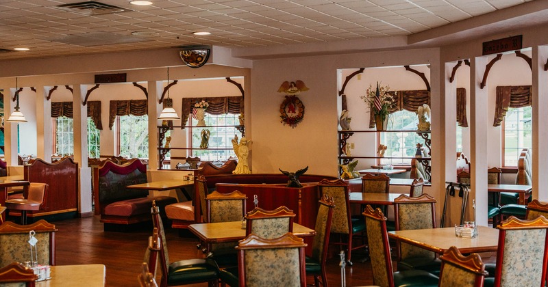 Interior of a warmly lit dining area with tables, chairs and booth seating