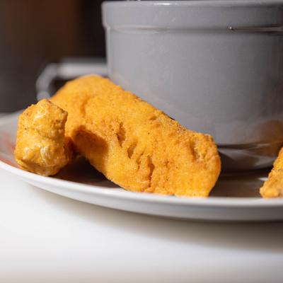 Fried fish served on a plate alongside a bowl of shrimp and grits, close-up.