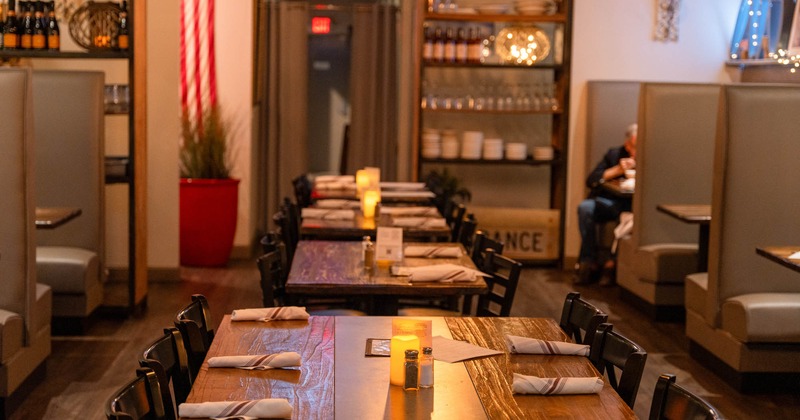 Interior, tables with chairs down the middle, seating booths on both sides, shelf in the back