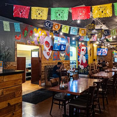 Vibrant interior with wooden tables, colorful murals, and papel picado decorations.