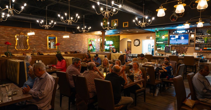 Interior, dining area with bar, chandeliers and moody lighting