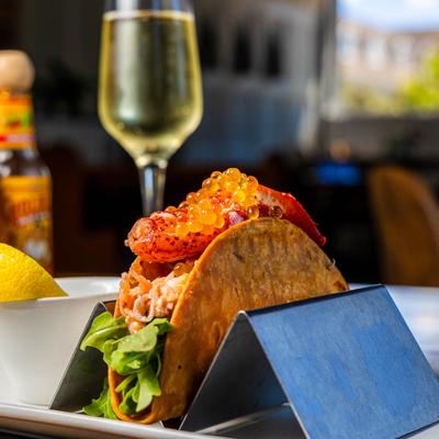 Champagne Buttered Lobster Taco with a glass of champagne in the background.
