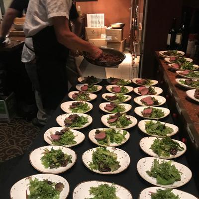 A person preparing many plates with served food