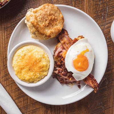 Top view of a plate with biscuit, ham, bacon, fired egg and pimento cheese