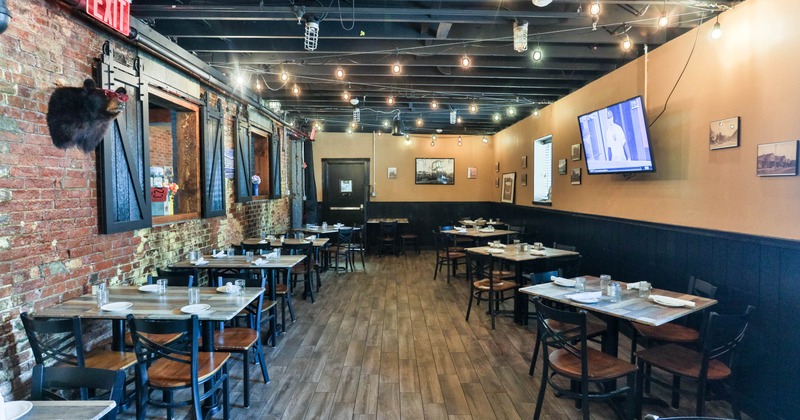 Interior, seating area, tables for four and two, exposed brick walls, TV on the wall