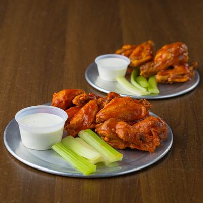 Chicken wings with celery sticks and ranch sauce.