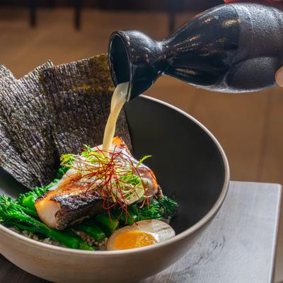 Ramen bowl with broth being poured.